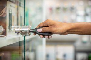 Hand, die ein OneKEY benutzt, um ein Schloss an einer Vitrine zu öffnen