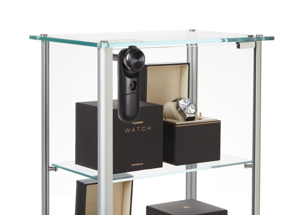 InVue LIVE Cam Lock an einer Glasvitrine befestigt, um die in Schachteln verpackten Smartwatches auf den Ausstellungsregalen zu sichern