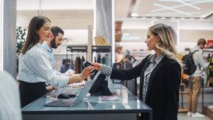 Ein Verkaufsmitarbeiter bearbeitet eine Kundenrückgabe an der Kasse und verdeutlicht damit, wie wichtig Rücknahmeprüfungsverfahren sind, um betrügerische Rückgaben und Bestandsverluste zu verhindern.