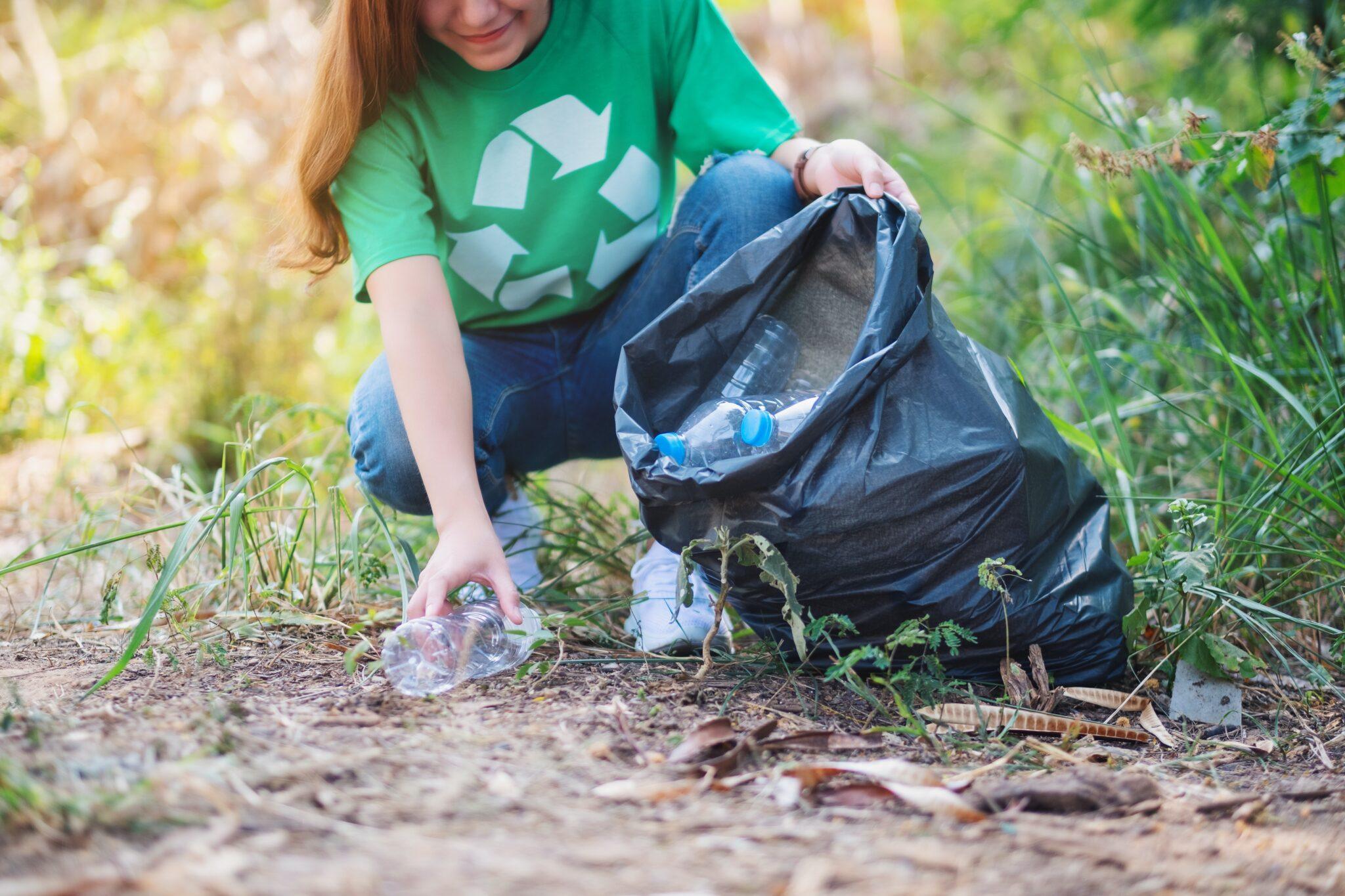 Frau sammelt Recyclingmaterial ein und wirft es in den Müll