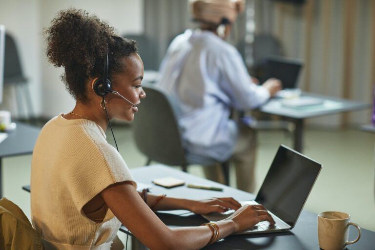 Frau sitzt an einem Laptop mit einem Headset für den Kundendienst