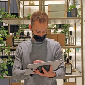 Mann mit Maske hält mobilen Tablet-Ständer