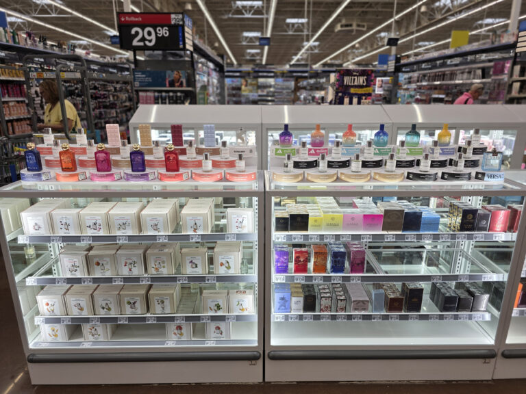 Eine Glasvitrine, in der Parfümverpackungen ausgestellt sind, und darauf Tester-Displays, an denen die Kunden die Düfte ausprobieren können.